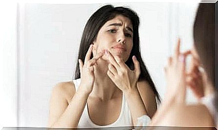 Girl squeezes a pimple in the mirror.