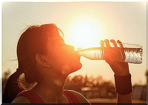 Sporty woman drinks water from a bottle