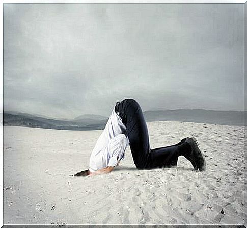 Man who is afraid and hides his head in the sand